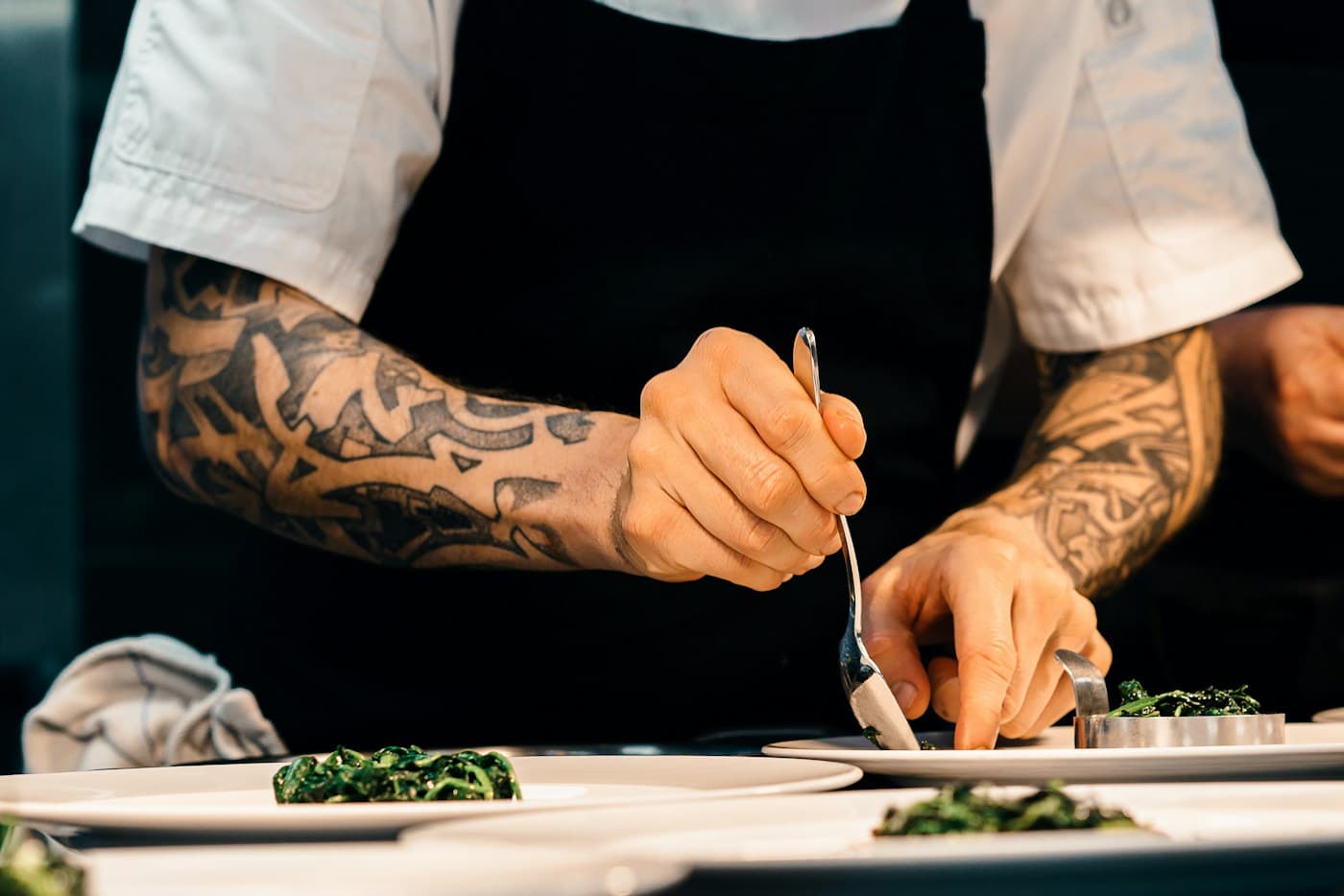 A chef plates food by hand in a working kitchen